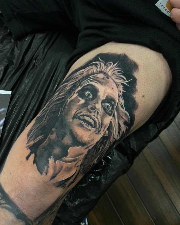 Black and grey Beetlejuice portrait tattoo on the upper arm