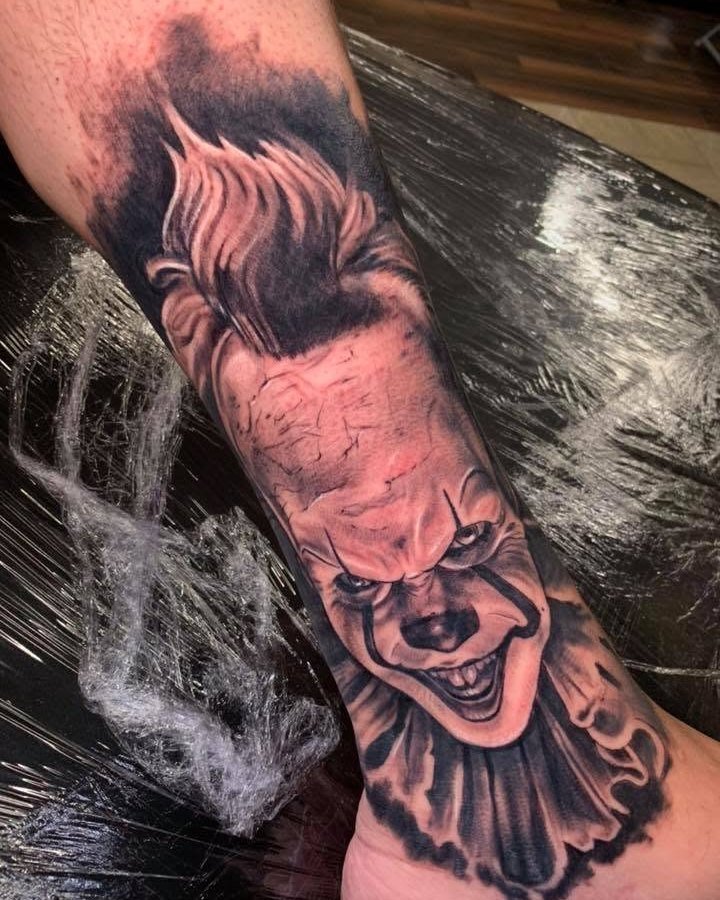 Black and grey Pennywise portrait tattoo on the arm