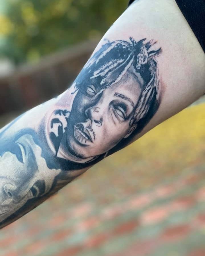 Black and grey tattoo of a woman's face and a statue on the forearm