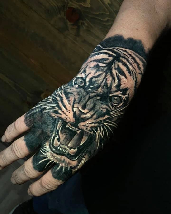 Black and grey roaring tiger tattoo across the hand