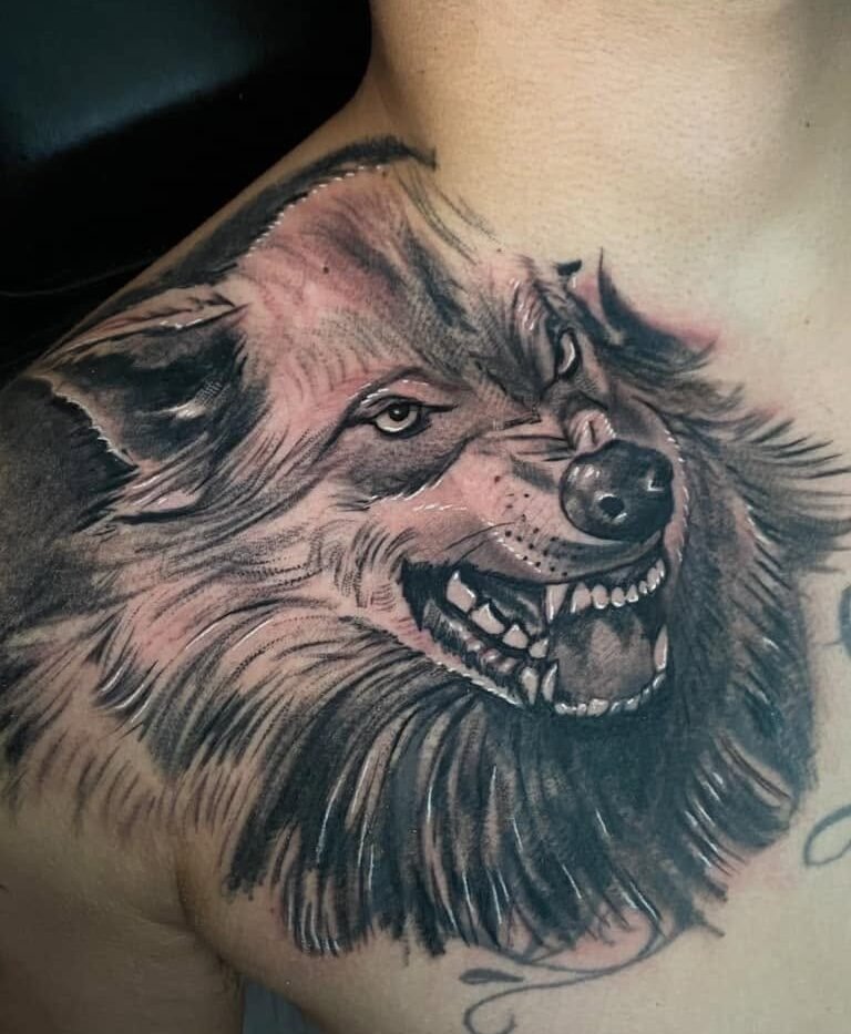 Black and grey wolf portrait tattoo on the chest